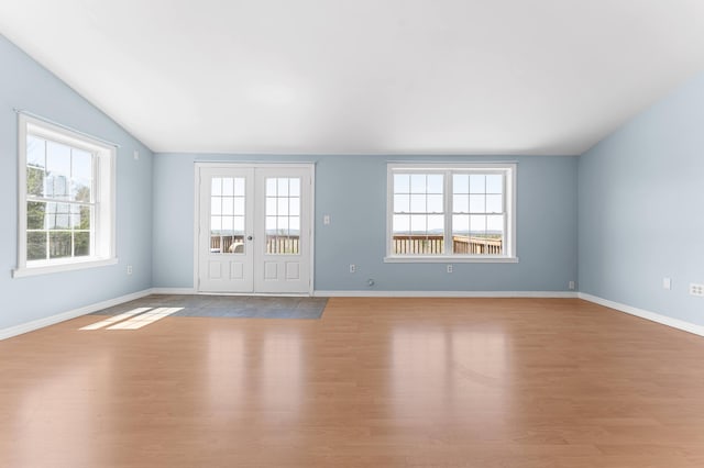unfurnished living room featuring baseboards, plenty of natural light, wood finished floors, and lofted ceiling