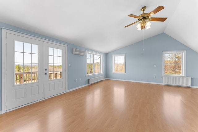 unfurnished living room with radiator heating unit, plenty of natural light, an AC wall unit, and wood finished floors