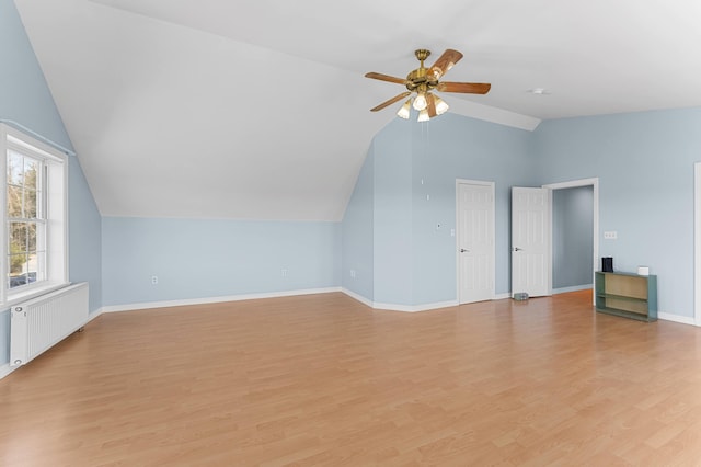 bonus room featuring radiator, lofted ceiling, baseboards, a ceiling fan, and light wood finished floors