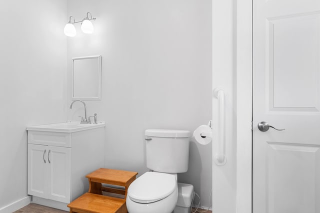half bath with vanity, baseboards, and toilet