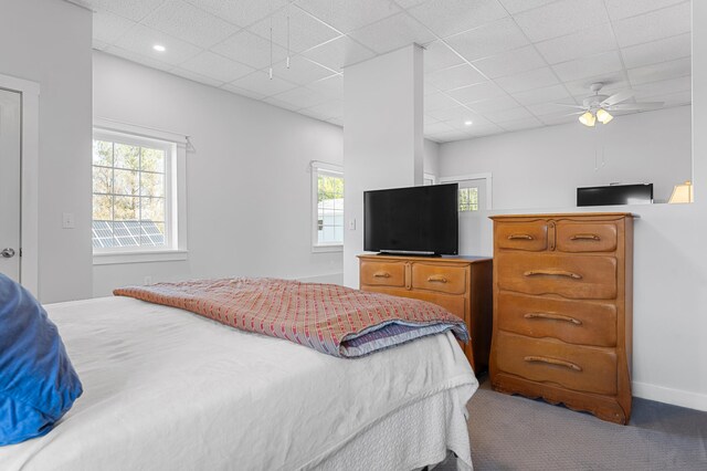 bedroom featuring carpet floors, baseboards, a ceiling fan, and a drop ceiling