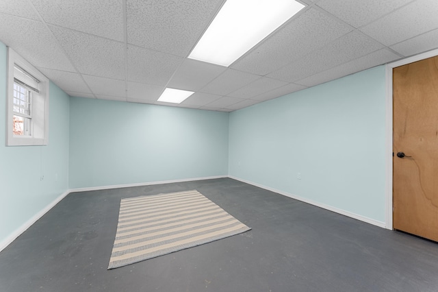 empty room with baseboards, concrete floors, and a paneled ceiling