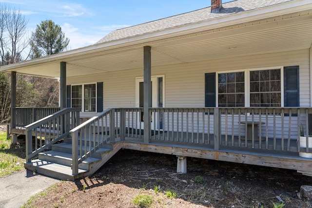 exterior space featuring roof with shingles, covered porch, and a chimney