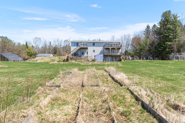rear view of property with stairs and a vegetable garden