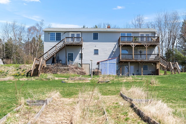 rear view of property featuring a deck, a vegetable garden, a chimney, a yard, and stairway