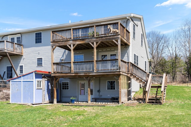 back of property featuring a lawn, stairs, an outbuilding, and a deck