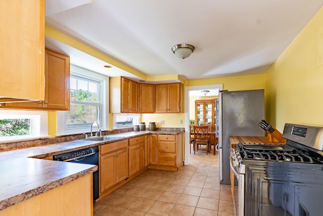 kitchen with a sink, light tile patterned floors, dishwasher, and gas stove