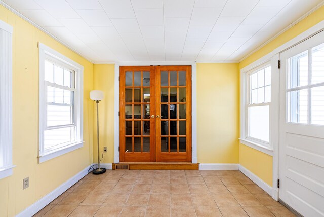interior space featuring crown molding, baseboards, light tile patterned floors, and visible vents