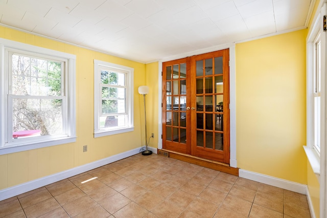 empty room featuring baseboards, french doors, and light tile patterned flooring