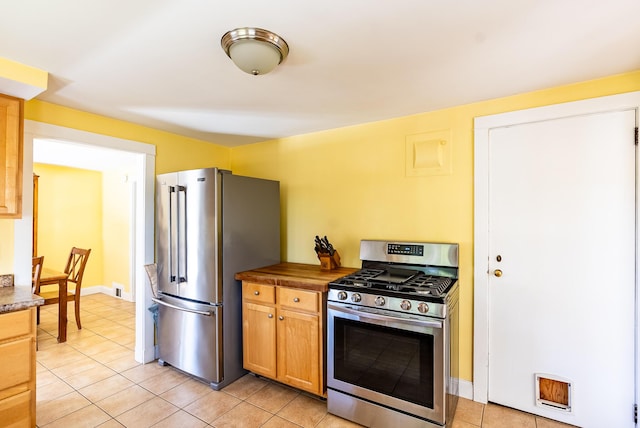 kitchen featuring baseboards, light tile patterned flooring, and stainless steel appliances