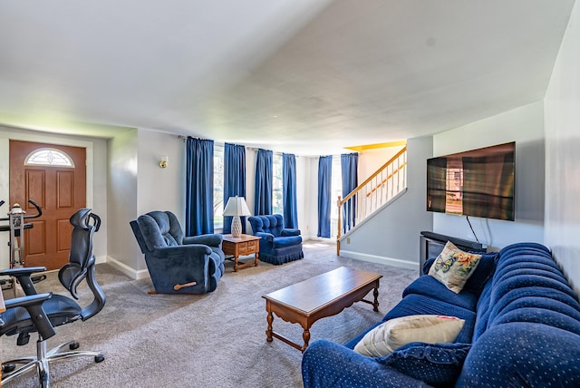 carpeted living area with stairs and baseboards