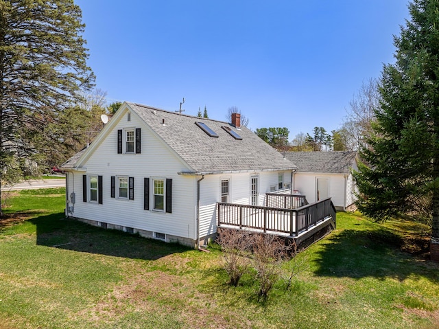 back of house featuring roof with shingles, a wooden deck, a chimney, and a yard