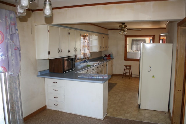 kitchen with dark countertops, a sink, tile patterned floors, freestanding refrigerator, and baseboards