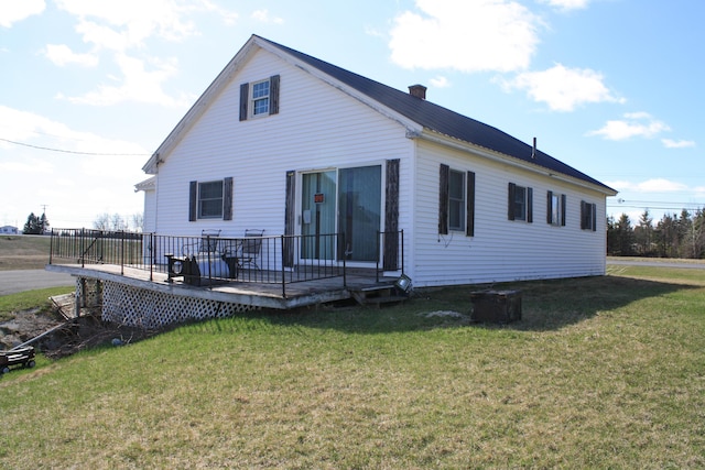 back of property with a yard, a deck, and a chimney