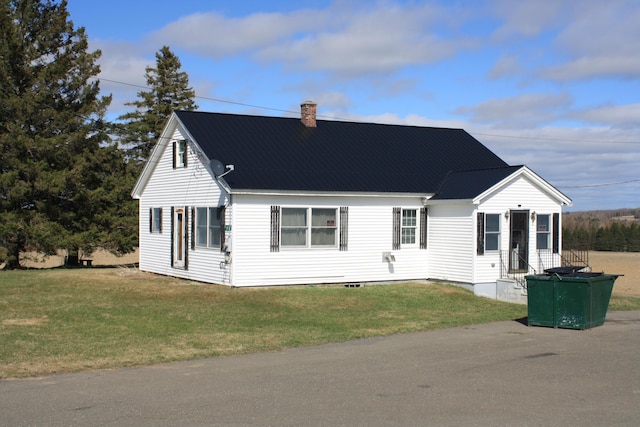 view of front of property featuring a front yard, a chimney, and metal roof