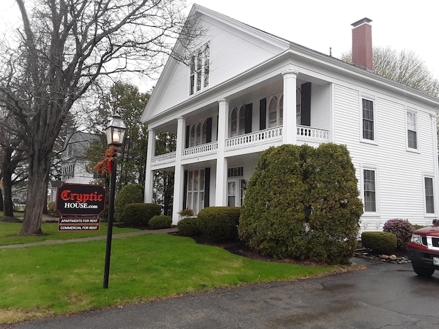 72 Main St, Orono, ME 04473 - view of front of property featuring a front lawn, a balcony, and a chimney