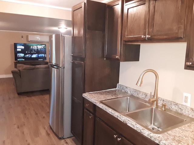 72 Main St, Orono, ME 04473 - kitchen with freestanding refrigerator, dark brown cabinetry, light countertops, a sink, and light wood finished floors