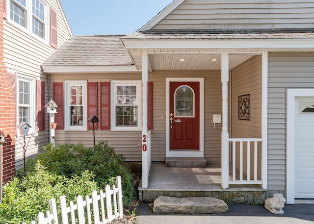 doorway to property with roof with shingles, fence, and a garage