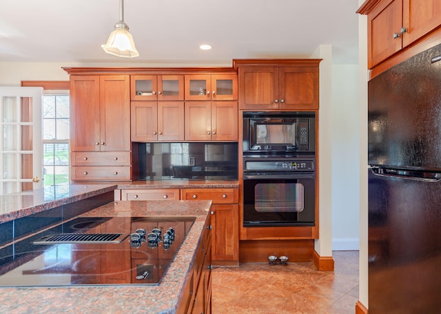 kitchen with stone counters, brown cabinetry, glass insert cabinets, and black appliances