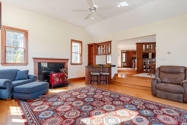 living area featuring a ceiling fan, lofted ceiling, a wealth of natural light, and light wood finished floors