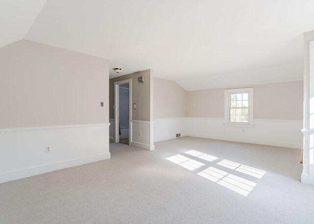 bonus room featuring visible vents, light colored carpet, and lofted ceiling