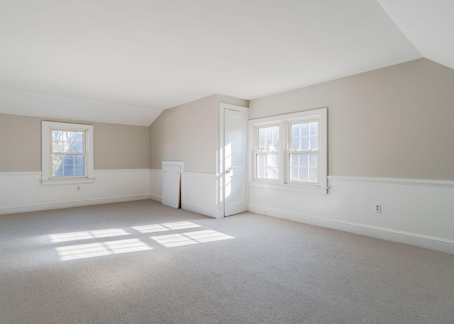bonus room with light carpet and vaulted ceiling
