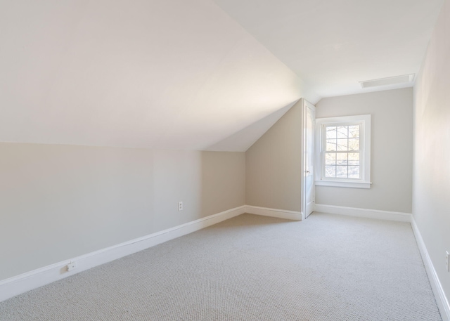 bonus room with baseboards, visible vents, vaulted ceiling, and light colored carpet
