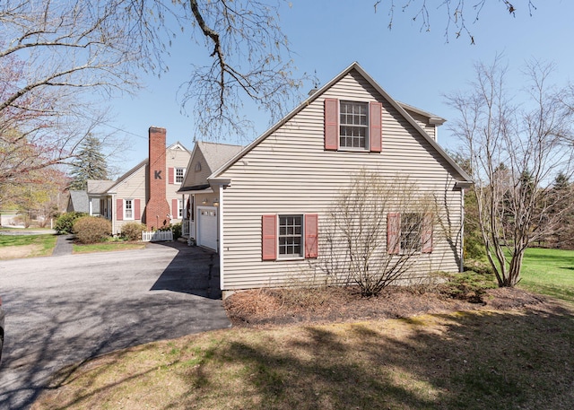 view of property exterior featuring a yard, an attached garage, and aphalt driveway