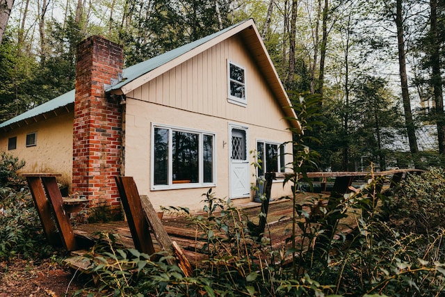 65 Pinecroft Rd, Harrison, ME 04040 - view of side of property featuring a deck, a chimney, stucco siding, and metal roof