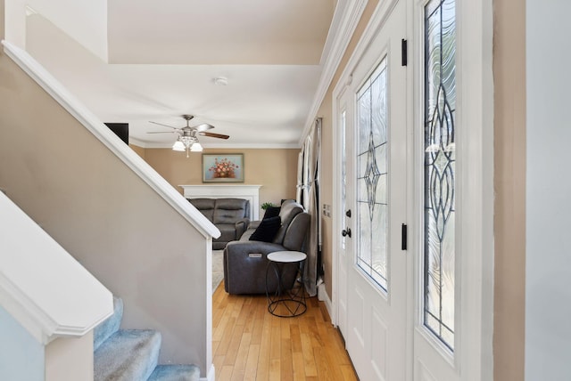 foyer with stairs, ceiling fan, crown molding, and light wood finished floors