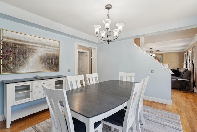 dining area featuring baseboards, light wood-style flooring, and ceiling fan with notable chandelier