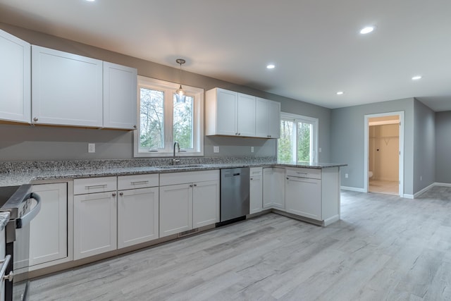 kitchen featuring a peninsula, a sink, stainless steel dishwasher, baseboards, and recessed lighting