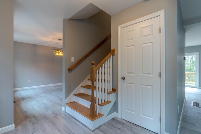 stairway with baseboards, a chandelier, visible vents, and wood finished floors