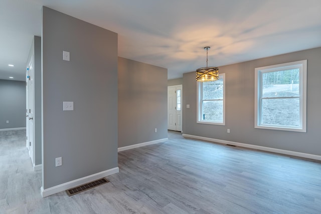 unfurnished room featuring baseboards, light wood finished floors, a chandelier, and visible vents