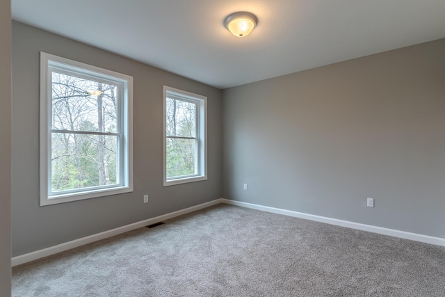 spare room featuring carpet flooring, visible vents, and baseboards