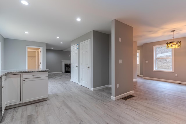 interior space with light wood-type flooring, a fireplace, and baseboards