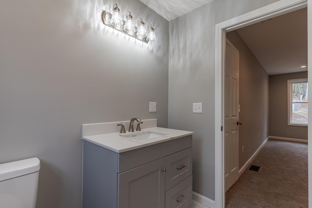 bathroom with toilet, visible vents, baseboards, and vanity