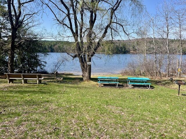 view of green lawn featuring a water view