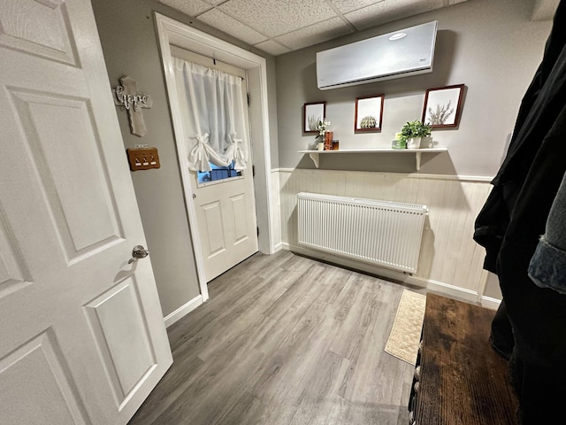 208 N Caribou Rd, Presque Isle, ME 04769 - entrance foyer featuring wainscoting, radiator heating unit, a drop ceiling, wood finished floors, and a wall mounted AC