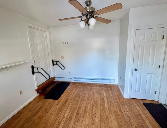 interior space with baseboards, a baseboard heating unit, and wood finished floors