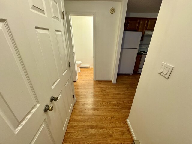 hall with light wood-style floors, baseboards, and a baseboard radiator