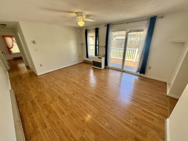 unfurnished room featuring heating unit, baseboards, a textured ceiling, a ceiling fan, and light wood-style flooring