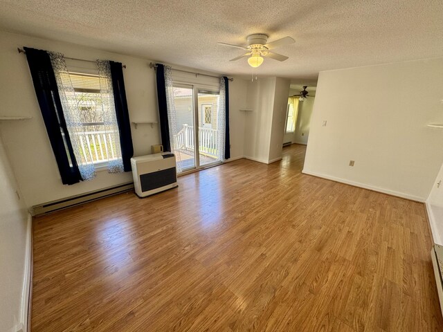 spare room featuring a ceiling fan, a textured ceiling, a baseboard heating unit, and light wood-style flooring