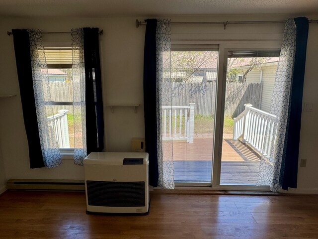 doorway to outside with baseboards, baseboard heating, and wood finished floors