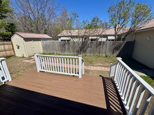 wooden terrace featuring an outbuilding, a fenced backyard, and a storage unit