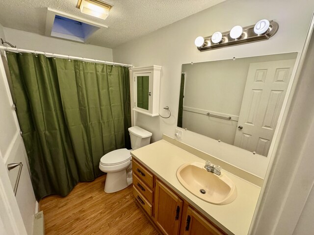 bathroom with vanity, toilet, a textured ceiling, a shower with shower curtain, and wood finished floors