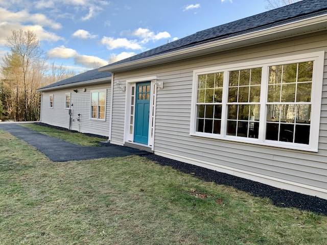 back of property with a lawn and roof with shingles