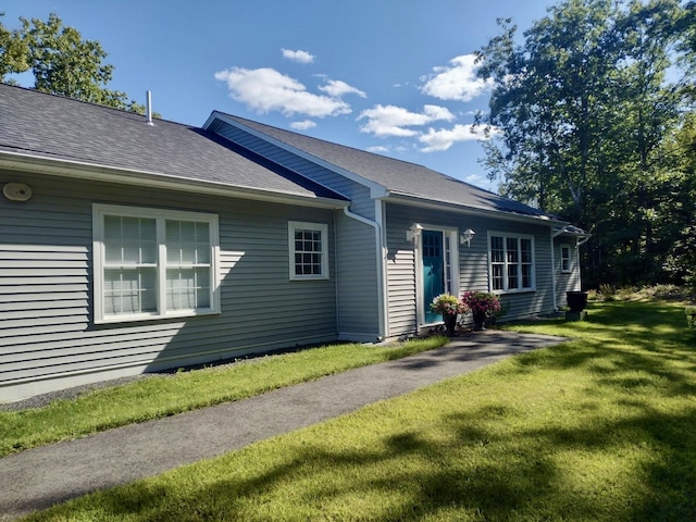 view of front of house with a front yard and a shingled roof