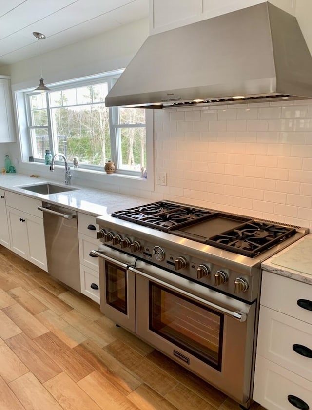 kitchen with stainless steel appliances, extractor fan, a sink, white cabinetry, and tasteful backsplash