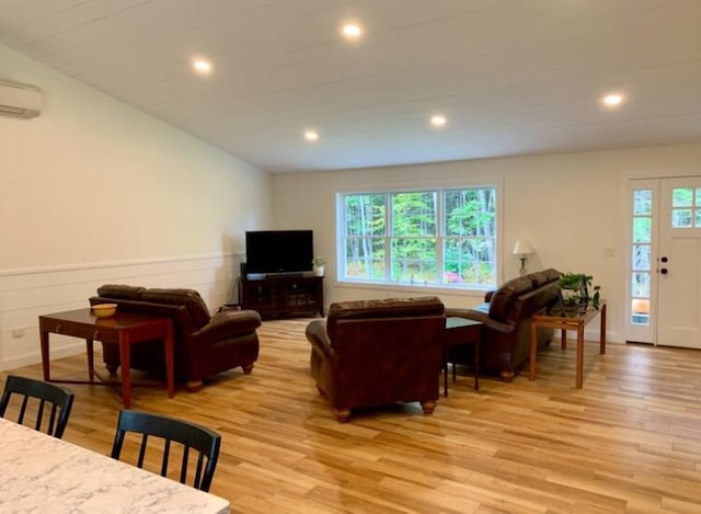 living room with light wood finished floors, recessed lighting, an AC wall unit, and a wainscoted wall